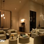 Modern living room with warm lighting, pendant fixtures, and contemporary seating, Lutron logo visible.